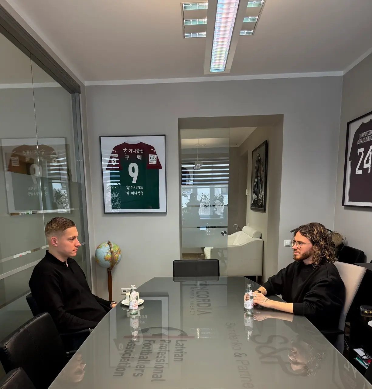 A meeting at a conference table in an office with framed football shirts